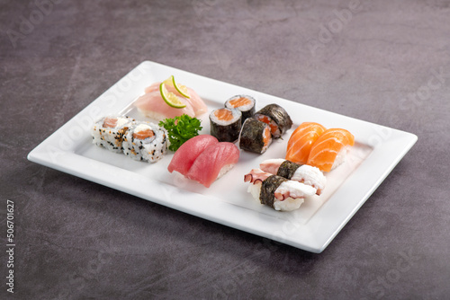 Sushi mix on white plate. Studio shoot isolated on slate background. Salmon, tuna, octopus and white fish different kinds of sushi. Oriental food on Brazilian way!