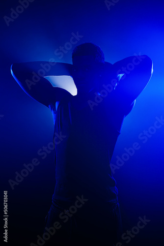 Basketball player holding a ball against blue fog background. African american man silhouette.