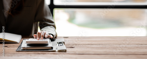 Photos Businessman using a calculator to calculate numbers on a company's financial documents, he is analyzing historical financial data to plan how to grow the company