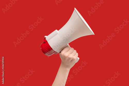 Megaphone in woman hands on a red background.