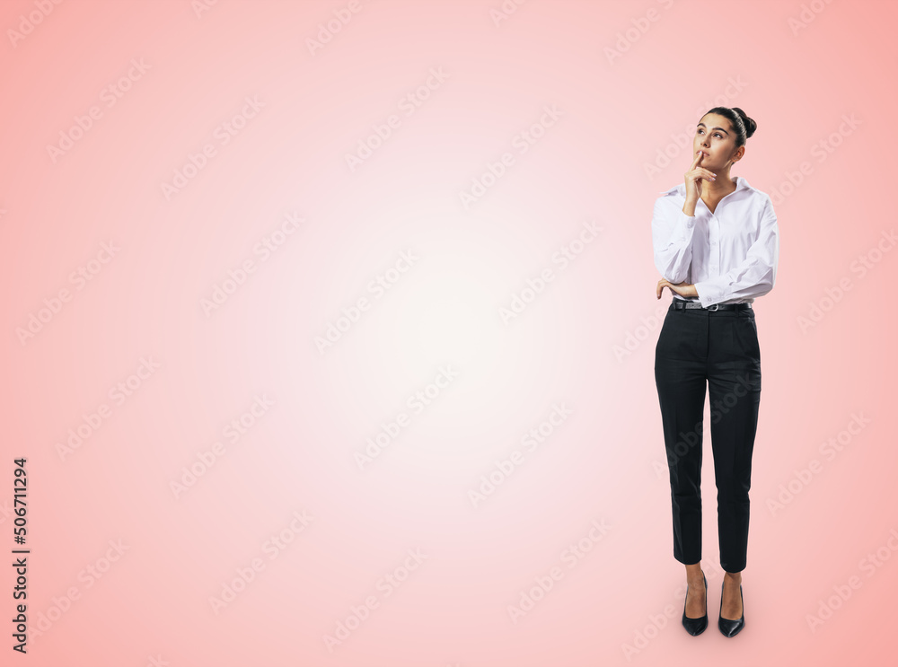 Thinking concept with pensive businesswoman in white shirt and dark trousers standing full length on abstract light pink wall backdrop, with empty place for you text, mock up - obrazy, fototapety, plakaty 