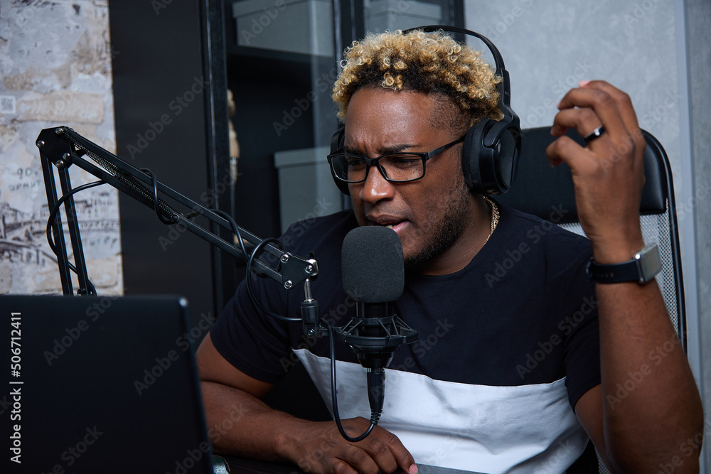 A close up of a young male radio host, who looks focused, speaks into ...
