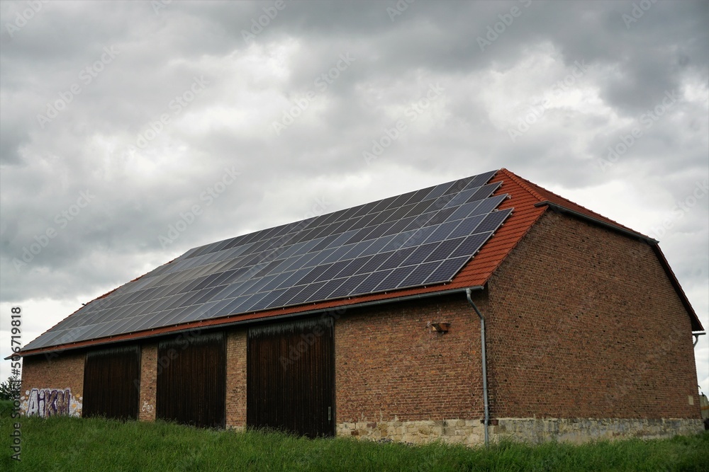 Alte Backsteinscheune mit Solardach vor Himmel im Frühling