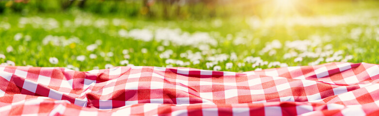 Closeup view of the picnic duvet on the meadow with green grass and spring flowers.