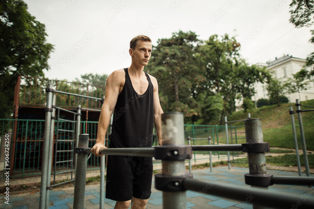 Fit man doing triceps dips on parallel bars at park exercising outdoors. Beautiful man doing work out and different exercises outdoor. Fit man doing triceps dips on parallel bars at park exercising outdoors. Beautiful man doing work out and different exercises outdoor.