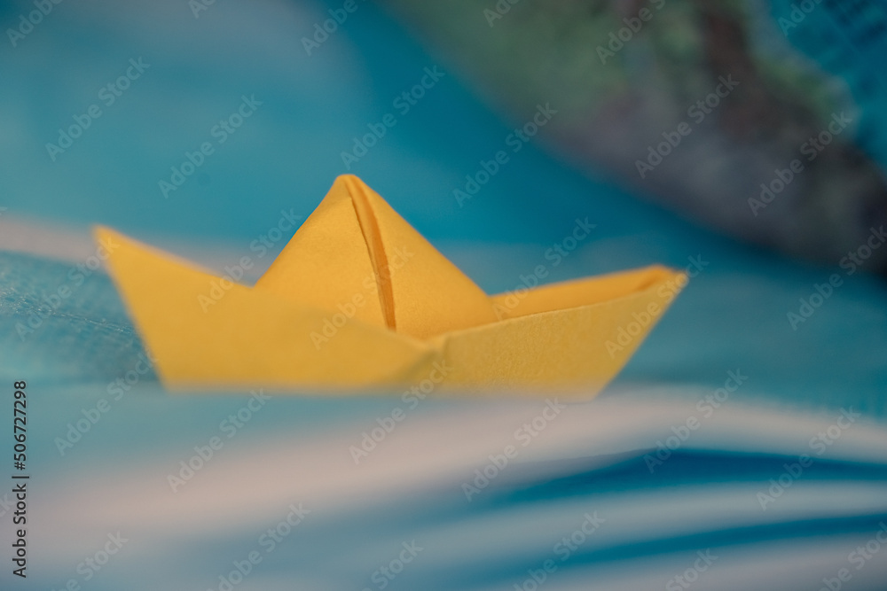 yellow origami boat sailing on a blue sea made with surgical masks.Pandemic problems concept, origami ship with surgical masks.