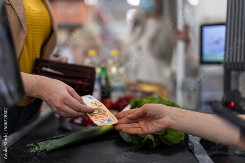 Obraz na plátně Close-up of woman giving money at the cash desk in supermarket