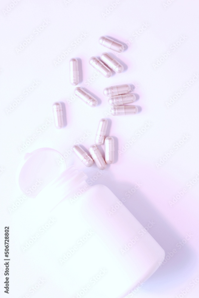 Gray pill capsules and pill bottles were placed on a white table. Gray pill capsules and pill bottles were placed on a white table.