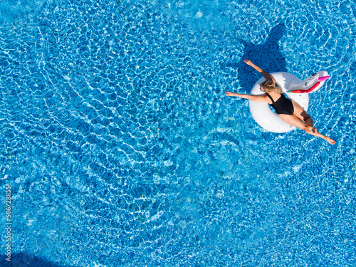 Beautiful woman on unicorn pool float in pool. Summer holidays