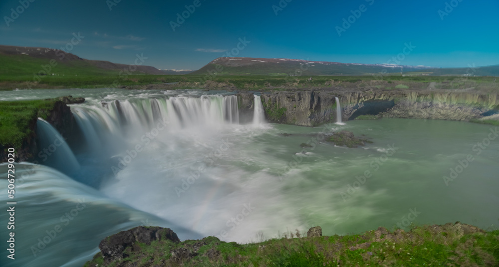 Fototapeta premium Long exposure photo of magnificent Godafoss waterfall in northern Iceland on a warm summer day. Visible frog from drops of water coming from the waterfall.