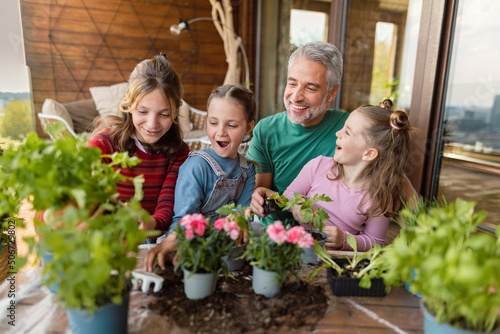 Three daughters helping father to plant flowers, home gardening concept