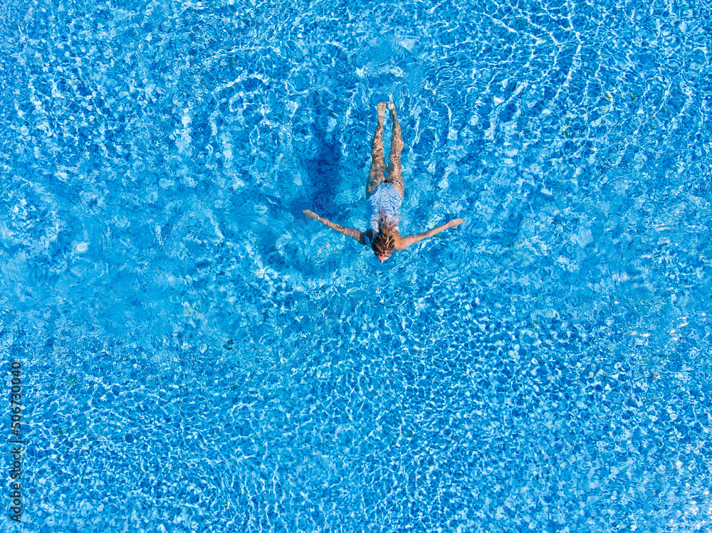 Aerial top view of woman in swimming pool water from above, summer vacation holiday concept, drone view