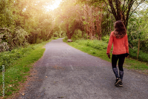 Women walking in a park on a small foot path. Outdoor activity and fitness. Sun flare. Selective focus.