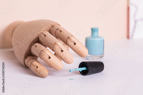 Wooden hand near blue gel polish. Manicure and nail care concept. 