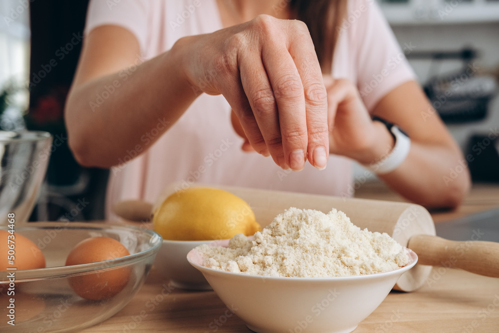 Fototapeta premium Woman cooking macaroon dessert. Egg lemon and almond flour on the table. the process of making cake, pancakes or meringue for breakfast. 