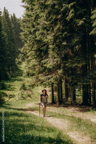 Summer trip to the mountains. A woman walks in the forest in summer. Hiking in the mountains. Active holiday in summer.