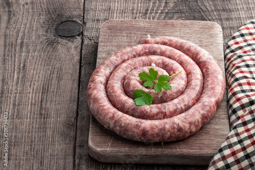 Raw thin pork sausages on wooden background