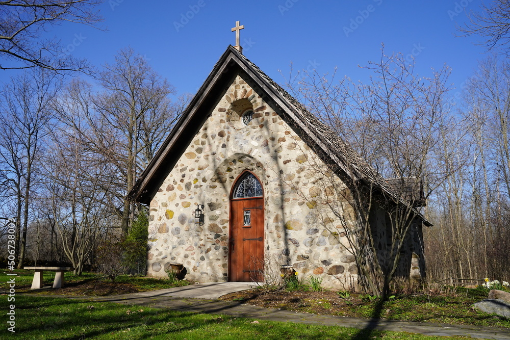 Historical old vintage abandoned mini stone church stands enclosed around a forest out in the countryside