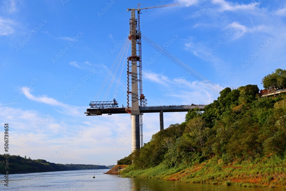 Construction of bridge over the Iguacu river on the border between Brazil and Paraguay. Bridge over the waters of the river near the Iguacu falls. Clear blue sky.