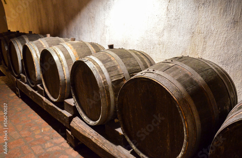 Row of wooden oak wine barrels in winery cellar. Wine is stored here to age before being bottled.