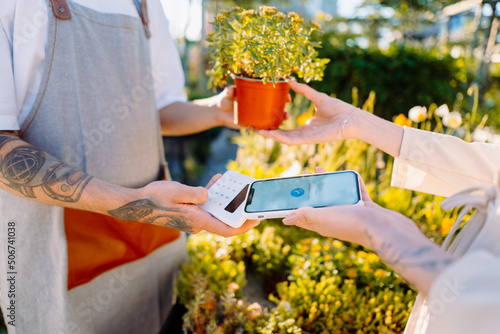 Woman in florist shop is paying with smartphone. Money transaction. Mobile Payment photo