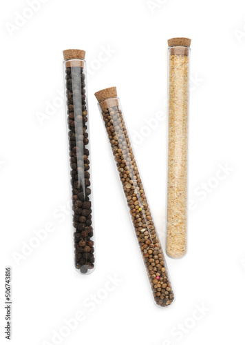 Glass tubes with coriander seeds, garlic powder and peppercorns on white background, top view