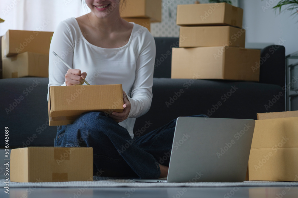 Small business entrepreneur receiving order on laptop computer and writing address on parcel box.. Small business entrepreneur receiving order on laptop computer and writing address on parcel box..