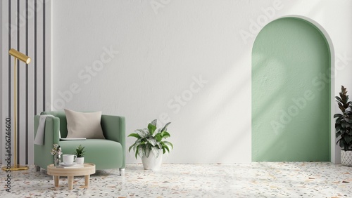 Green armchair with table on green wall and white terrazzo flooring.