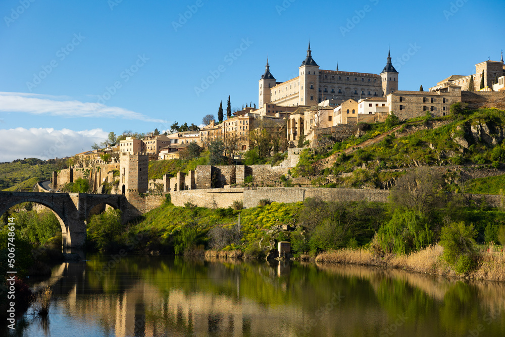Picturesque landscape with a view of the Alcantara Bridge, spanning the Tagus River, and the ancient Alcazar de Toledo ..Castle, located in the upper part of the city of Toledo, Spain