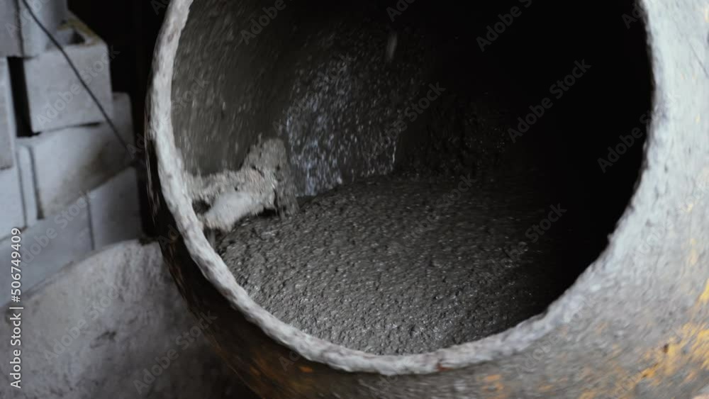 Concrete mixer stirs the building mixture. Rotating construction tool close-up. Construction work with gray construction adhesive Concrete mixer stirs the building mixture. Rotating construction tool close-up. Construction work with gray construction adhesive