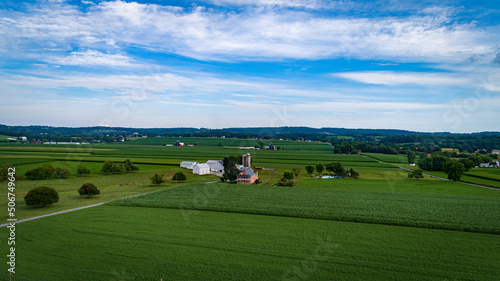 Aerial View of Farmlands With Barns and Silos, Looking Over the Hills and Fields of Rich Crops Growing on a Sunny Summer Day