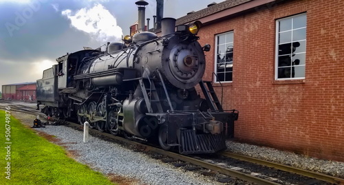 A Restored Steam Engine Getting Ready for Service, Blowing Smoke and Steam on a Cloudy Summer Day