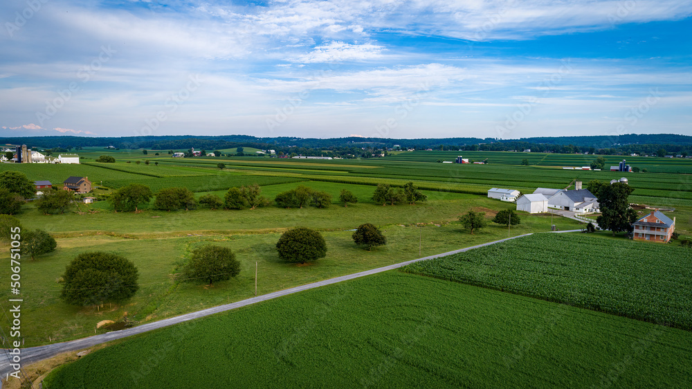Aerial View of Farmlands With Barns and Silos, Looking Over the Hills and Fields of Rich Crops Growing on a Sunny Summer Day Aerial View of Farmlands With Barns and Silos, Looking Over the Hills and Fields of Rich Crops Growing on a Sunny Summer Day