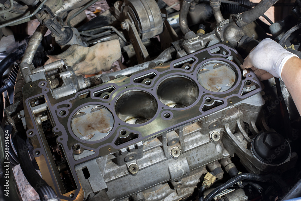 Auto mechanic working in garage. Repair service. The connecting rod, piston and cylinder block in a disassembled condition. maintenance repair at car service station for diagnosis Auto mechanic working in garage. Repair service. The connecting rod, piston and cylinder block in a disassembled condition. maintenance repair at car service station for diagnosis