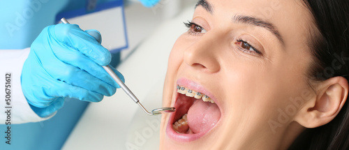 Beautiful woman with dental braces visiting dentist in clinic, closeup