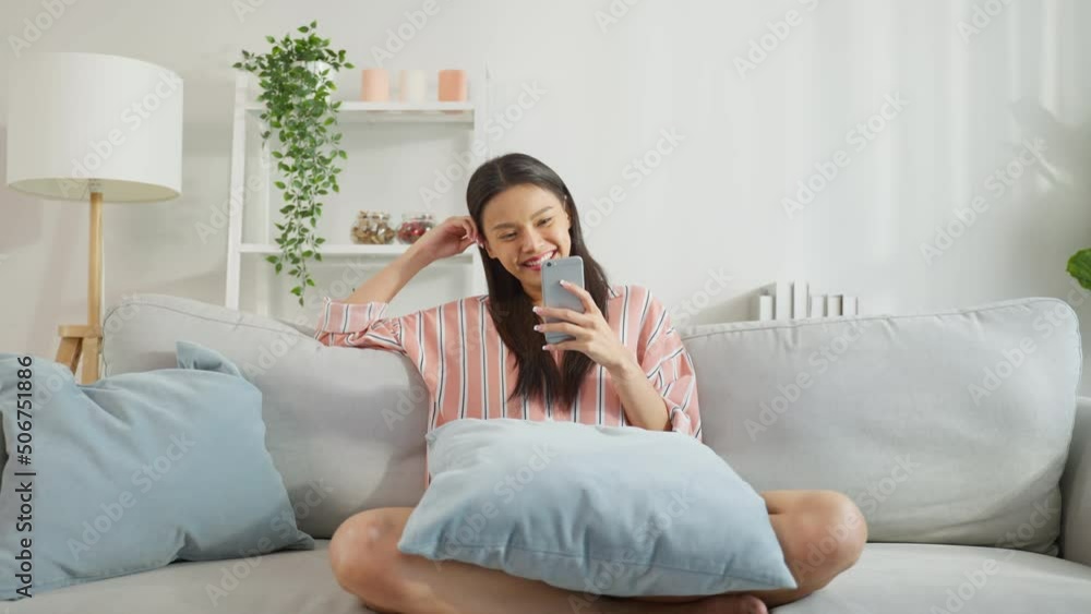 Asian beautiful woman sitting on sofa and swipe mobile phone in house. Asian beautiful woman sitting on sofa and swipe mobile phone in house.