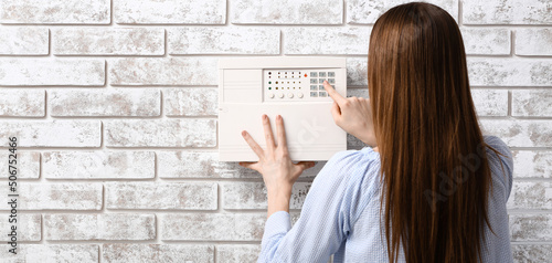 Young woman using smart home security system in room