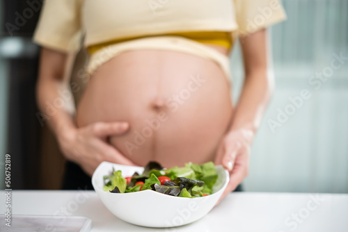 Close up of Asian woman pregnant standing and holding vegetable salad.