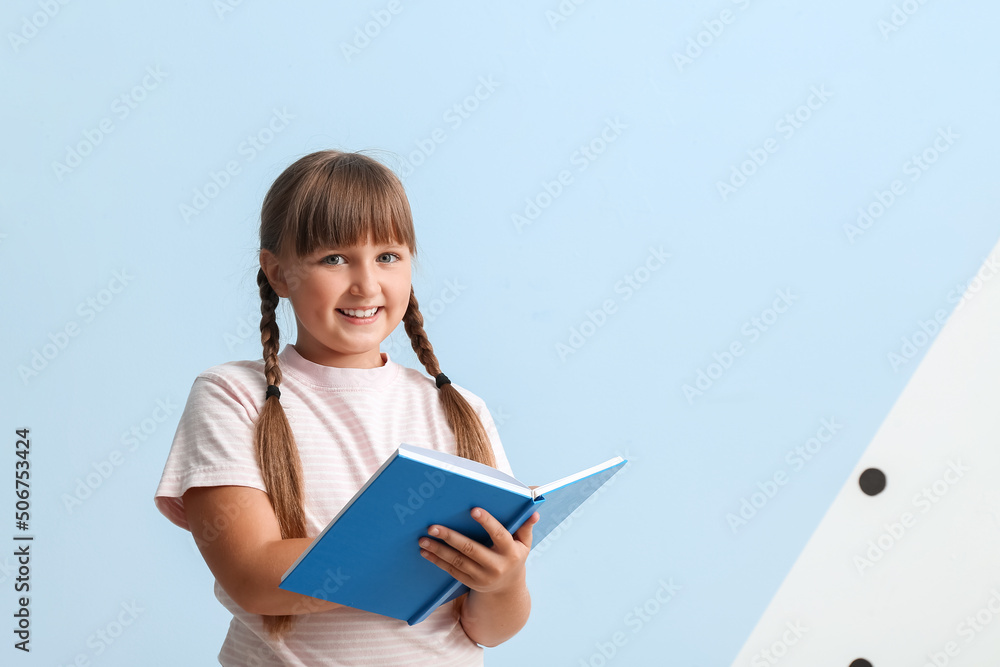 Little girl with braids reading book on blue background Little girl with braids reading book on blue background