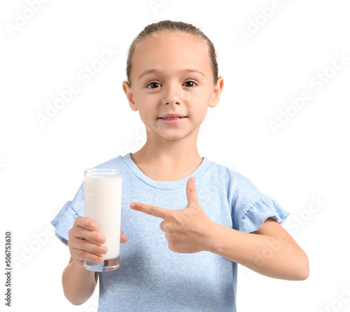 Little girl pointing at glass of milk on white background