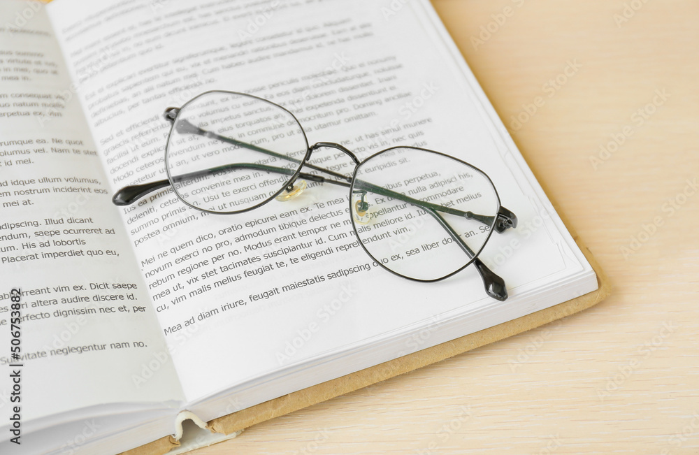Book with eyeglasses on wooden tray, closeup Book with eyeglasses on wooden tray, closeup