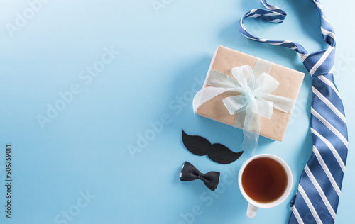 Happy Fathers Day background concept with gift box, decorated bow tie, necktie and mustache on bright pastel background.