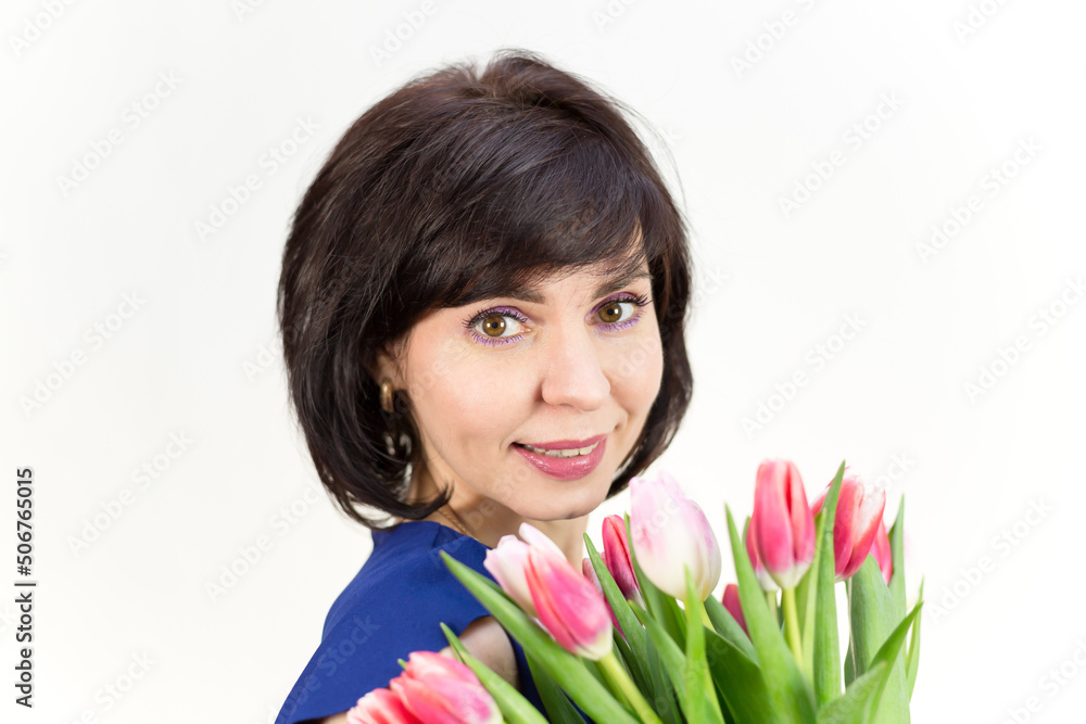 Portrait of an adult woman smiling brunette 40-45 years old with a bouquet of tulips on a white background. Portrait of an adult woman smiling brunette 40-45 years old with a bouquet of tulips on a white background.