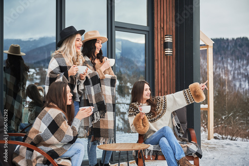 Fotografiet Young women enjoying winter weekends on terrace of contemporary barn house