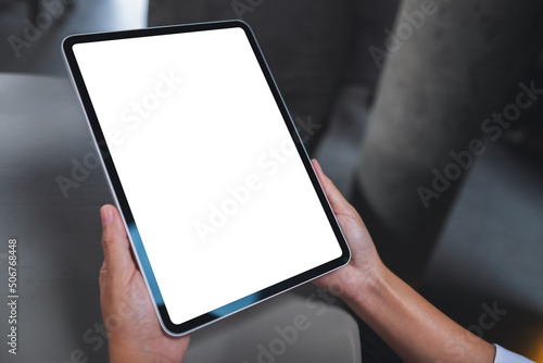 Mockup image of a woman holding digital tablet with blank white desktop screen in office