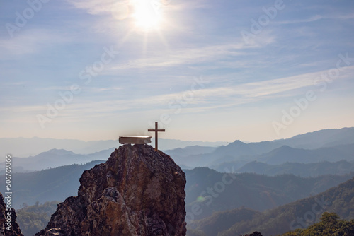 crucifix symbol and bible on top mountain with bright sunbeam on the colorful sky background