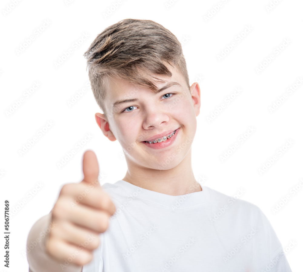Orthodontic treatment. Dental Care Concept. Young smiling boy with brackets shows thumbs up gesture. Isolated on white background Orthodontic treatment. Dental Care Concept. Young smiling boy with brackets shows thumbs up gesture. Isolated on white background