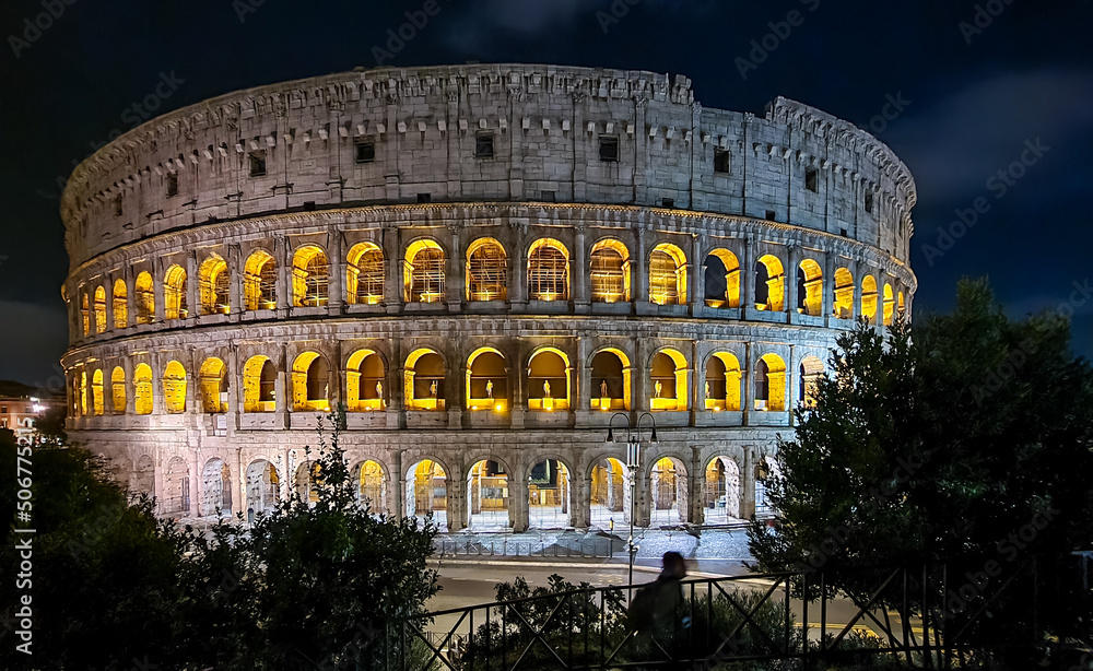 Wide angle view at night of illuminated exterior facade of famous Colosseum (Coloseo) of city of Rome, Lazio, Italy, Europe. UNESCO World Heritage Site. Flavian Amphitheater of ancient Roman Empire