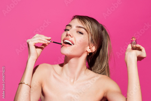 Beautiful young girl face with make up, isolated studio background. Fashion and beauty woman, makeup, cosmetics. Young woman applies lipstick on lips.