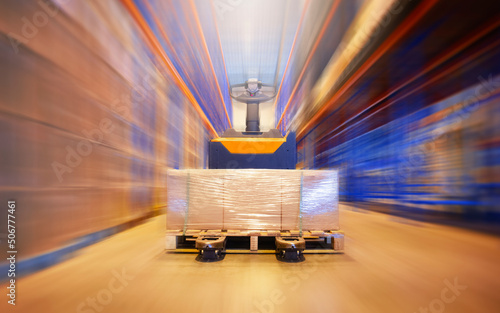 Cargo Boxes Pallet with Electric Forklift Pallet Jack in Blurred Warehouse. Shipping Warehouse. Tall Shelf Storage. Supplies Warehouse. Shipment Boxes.